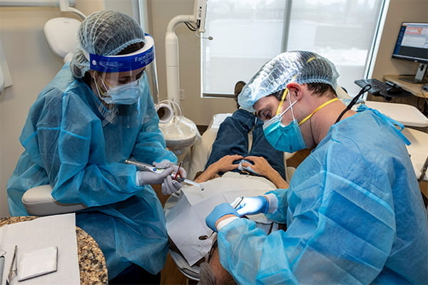 Two dentists cleaning a patients teeth